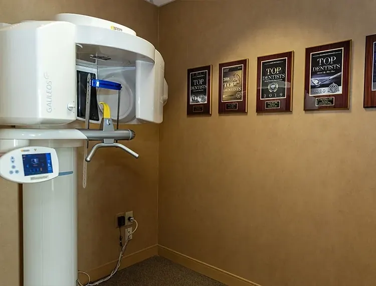 The cone beam CT scanner at Main Line Dental Group, beside a wall of Top Dentist plaques.