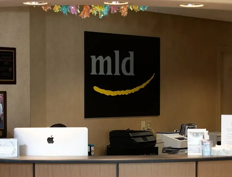 The front desk at Main Line Dental Group, with the mld logo on the wall behind it.