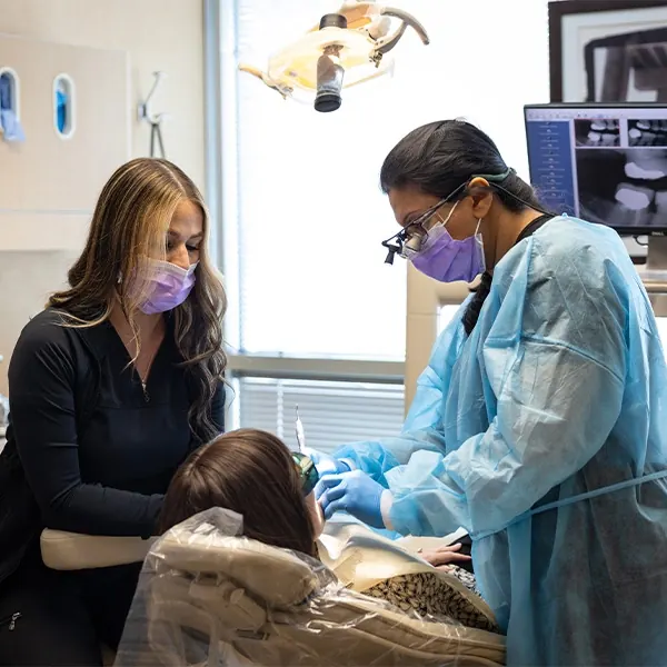 A dentist and assistant treating a patient's gums.