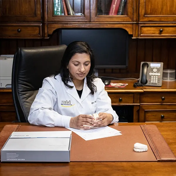 A dentist at her desk with a model of a patient's teeth.
