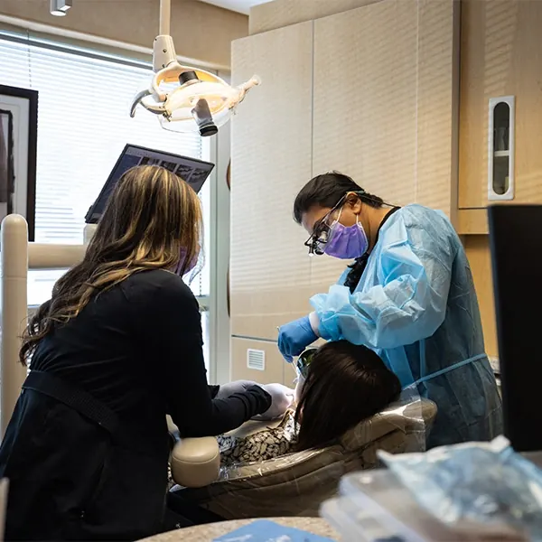 A dentist and an assistant treating a patient.